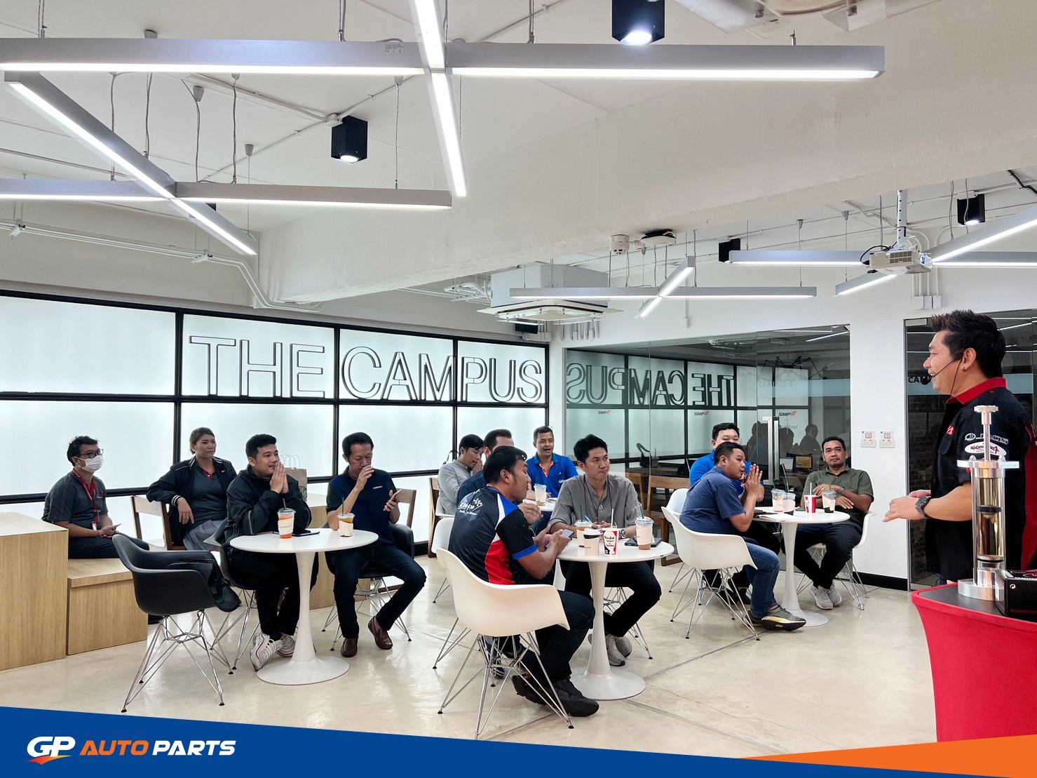 พนักงานและลูกค้ายืนพูดคุยกันภายในร้านอะไหล่ GP Autoparts ที่ตกแต่งทันสมัย