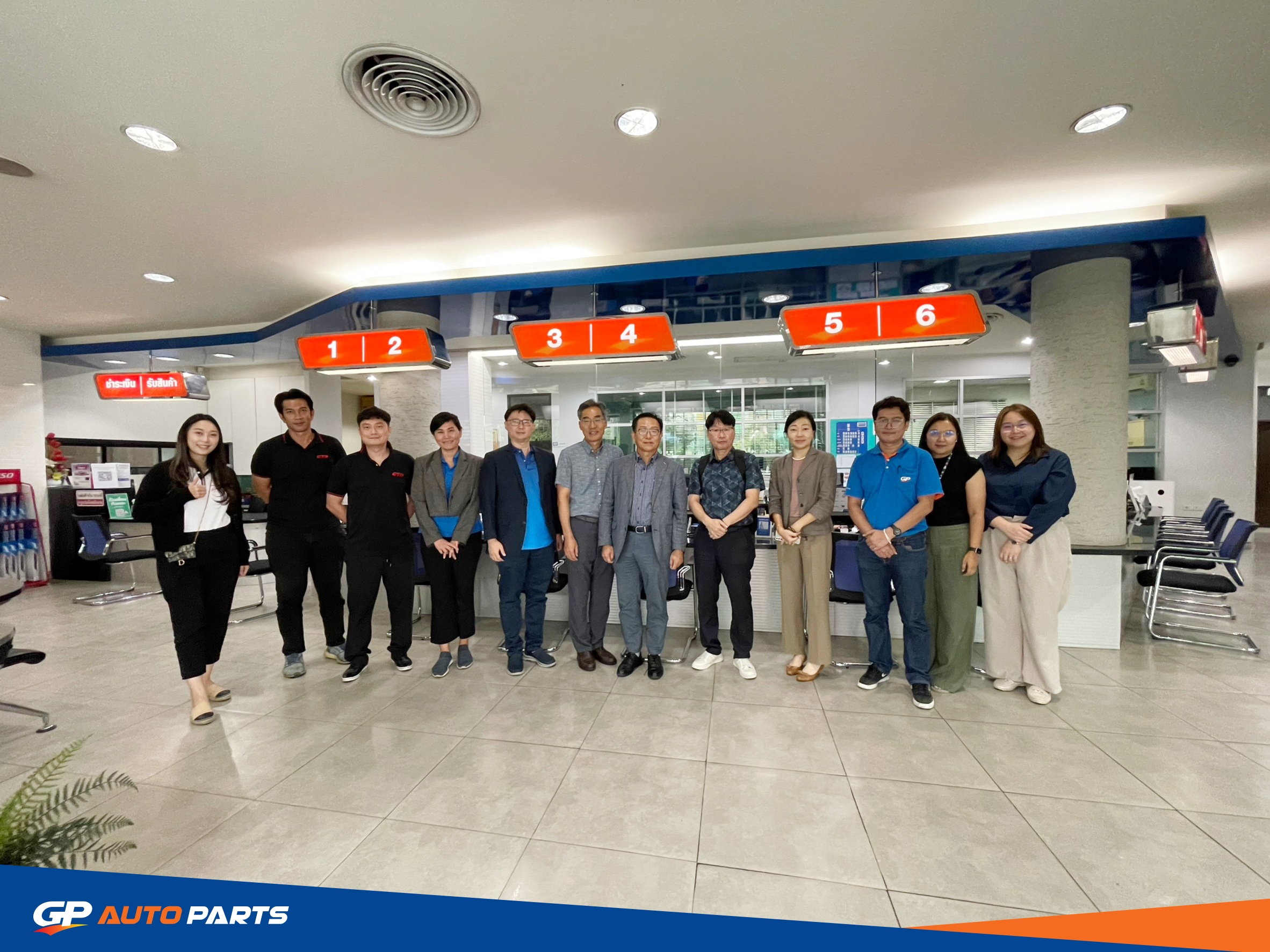 พนักงาน GP Autoparts ยืนต้อนรับภายในโชว์รูม/สำนักงานที่ตกแต่งด้วยโทนสีแดง-น้ำเงิน